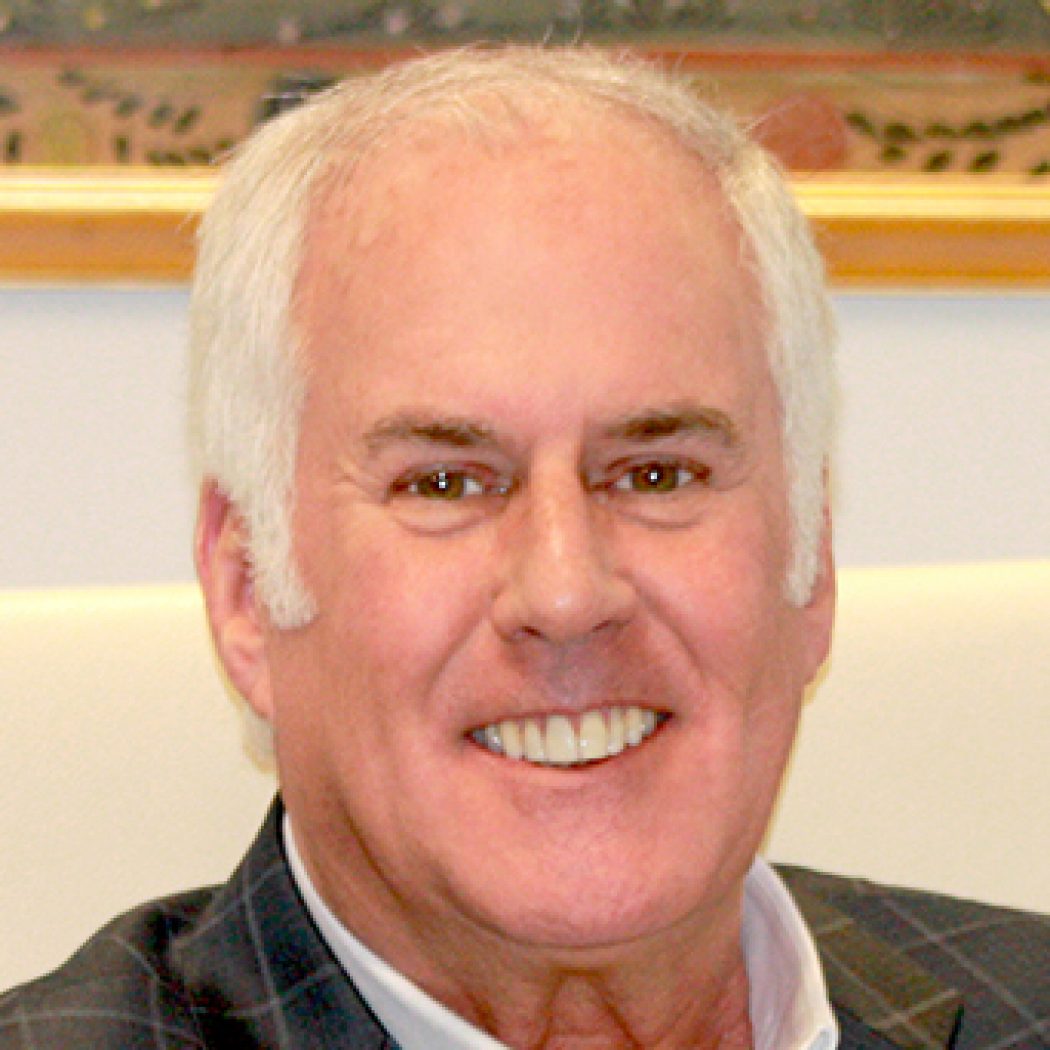 Headshot of David Weiss. Smiling man with gray hair in a plaid suit.