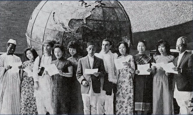 Black and white of a group of international students in their national dress in front of the historic SFS globe.