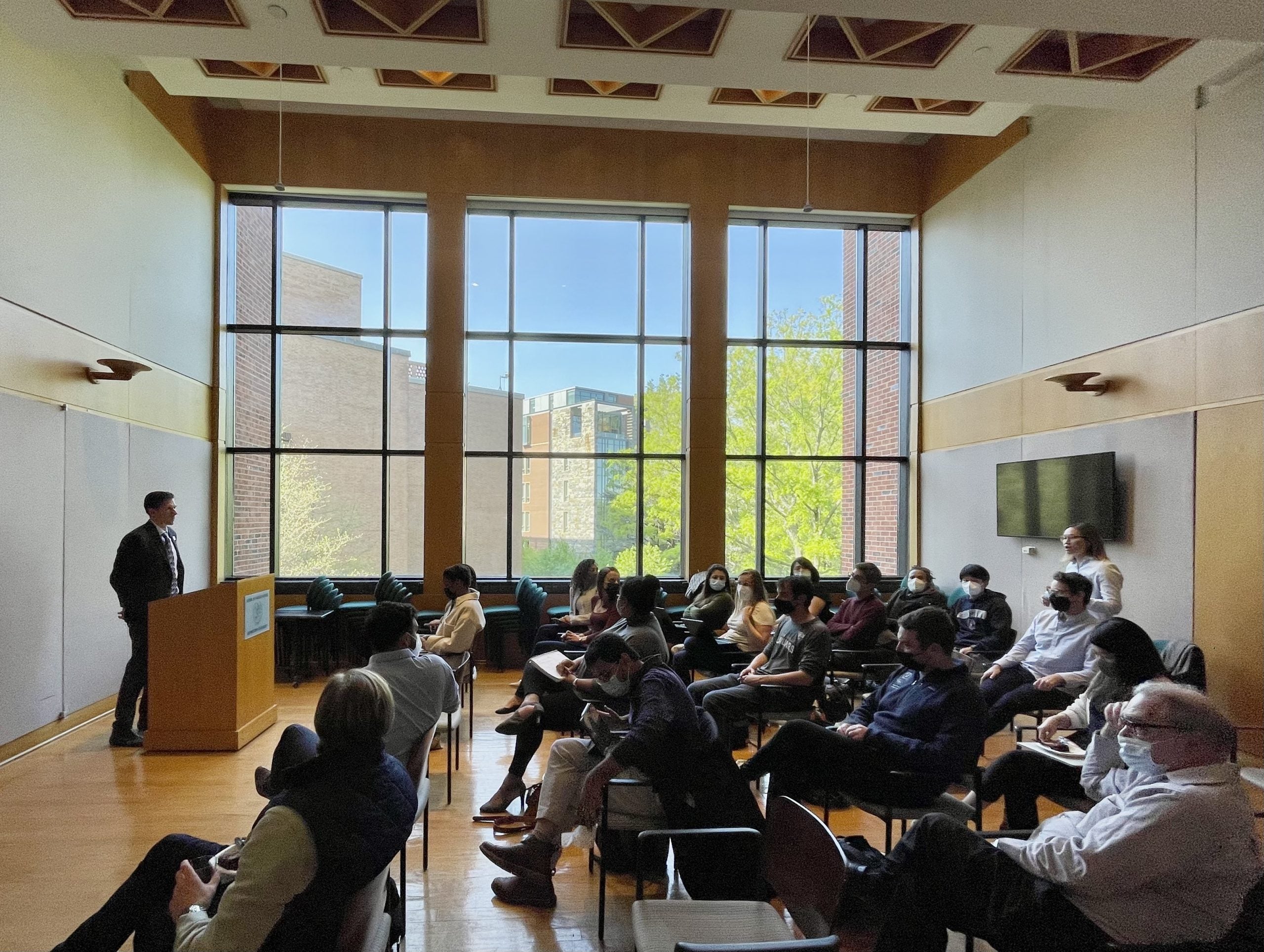 A group of alumni and faculty listen to a guest speaker in the 7th floor ICC conference room