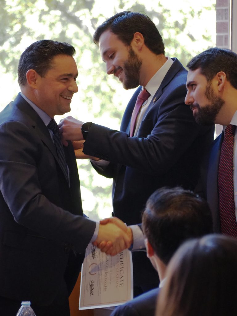 Rafael gives Ambassador Vecchio a pin as the Ambassador shakes hands with MSFS second-year, Carlos. 
